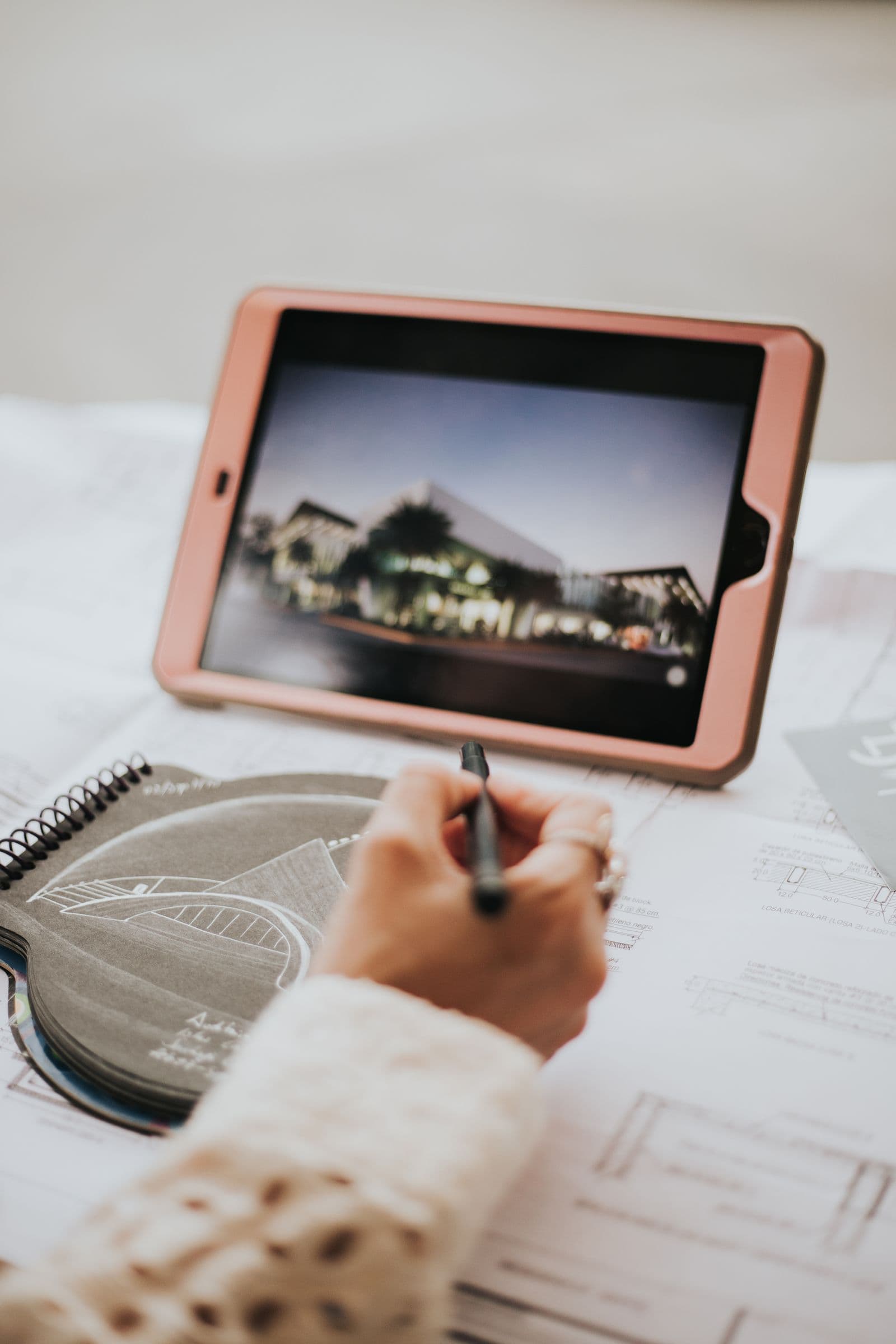 Tekenaar werkt een bouwtekening snel uit met tablet en schetsboek